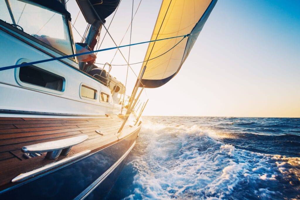 side view of sailboat sailing into the sunrise